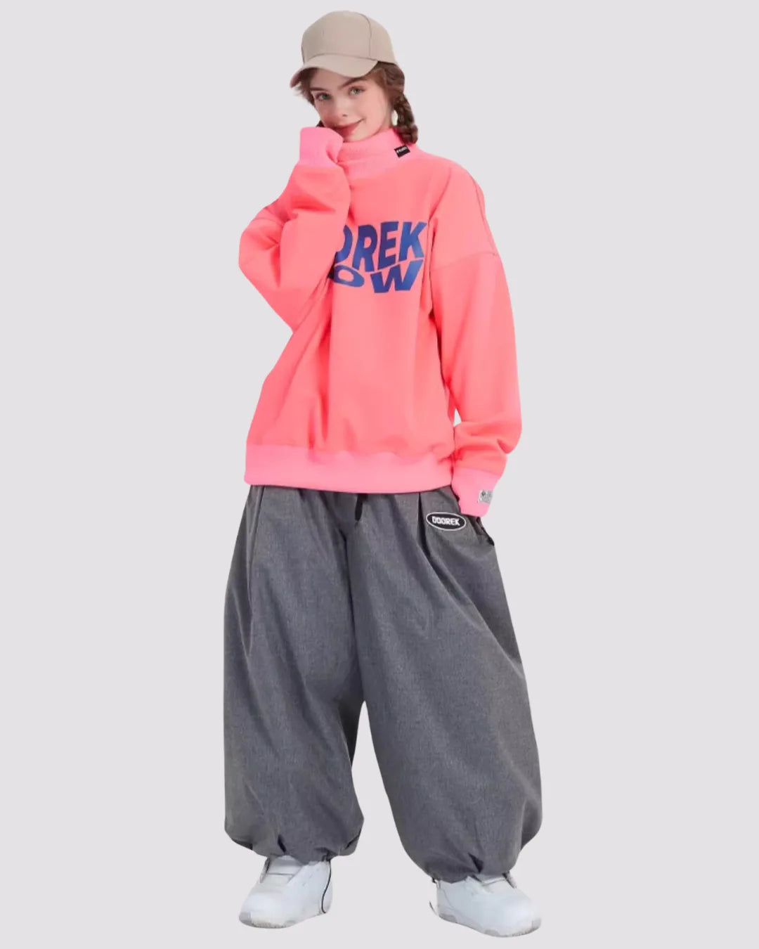 Woman wearing oversized grey baggy snowboard trousers and a bright pink sweatshirt, styled for winter sports 