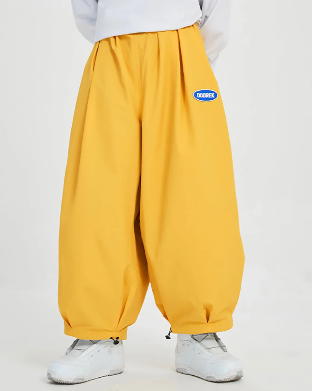 Close-up of loose-fit yellow trousers with elasticized cuffs and a waterproof badge