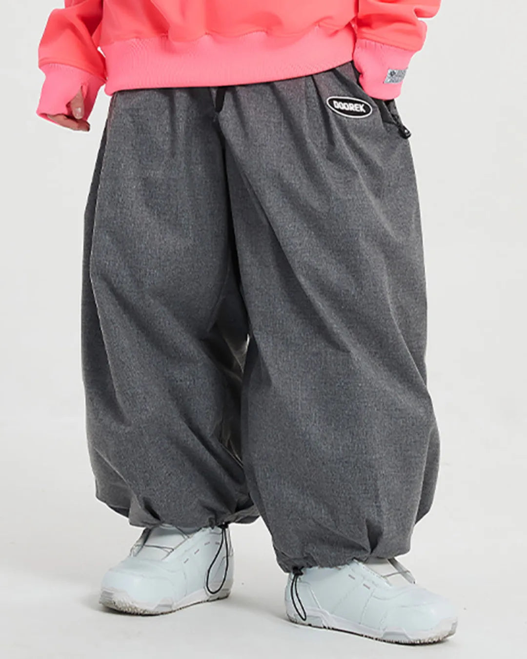 Close-up of grey loose-fit trousers styled with a pink sweatshirt and white sneakers