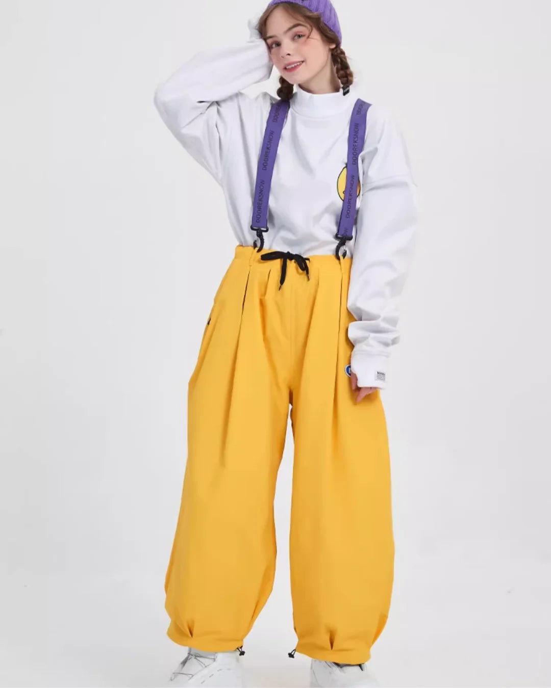 Yellow trousers with adjustable straps, styled with a white sweatshirt and a playful purple headband.